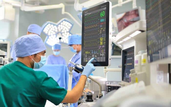 Medizinisches Personal im OP mit Geräten zur Luft- und Hygienekontrolle, Filter und Klimatechnik sichtbar.