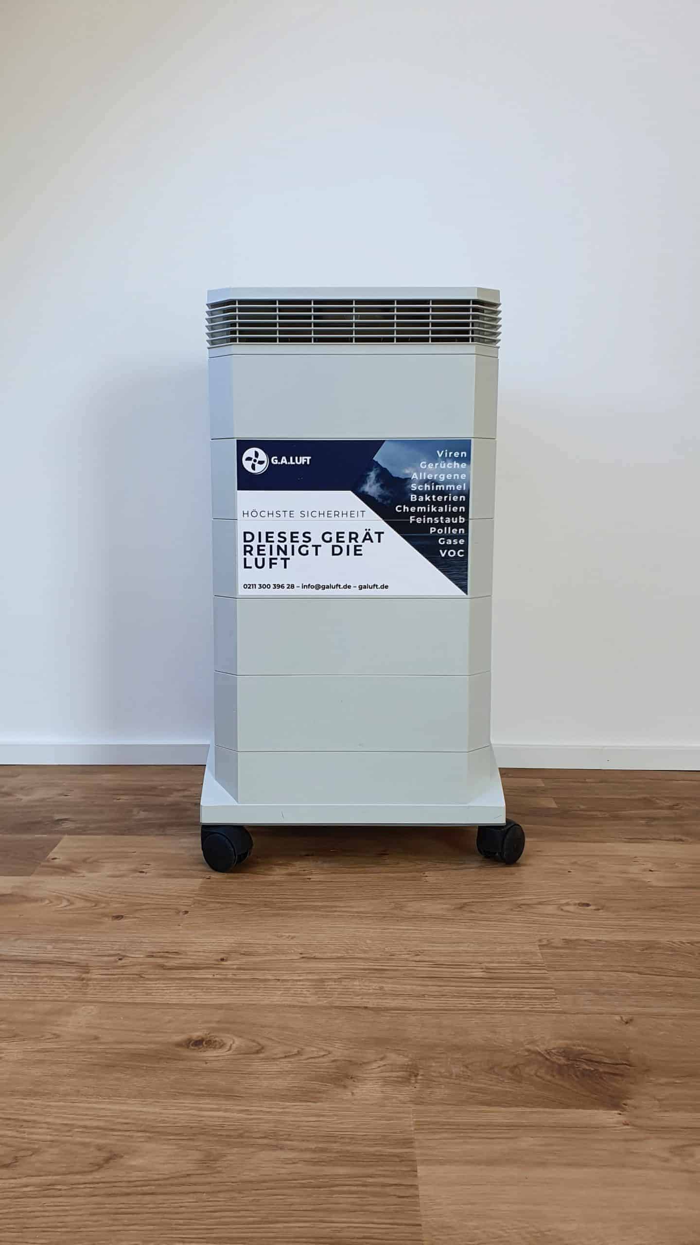 Grauer G.A.Luft Luftreiniger, Modell mit Rollen, vor weißer Wand. Ideal für schnelle Miete.