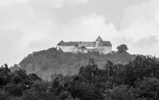 Schwarzweißaufnahme einer Burg in Hessen. Förderung für Luftreiniger in Hessen. Burg auf Hügel, umgeben von Wald.
