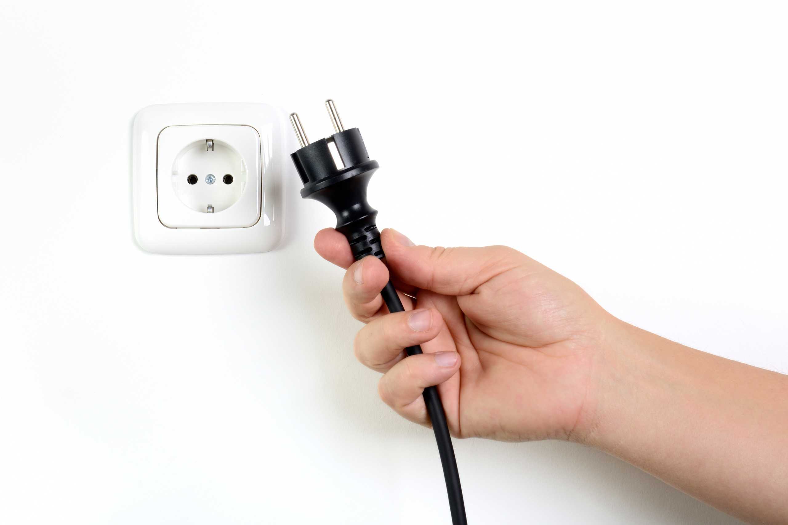 Luftreiniger Stromverbrauch Hand hält Stecker vor Steckdose. Luftreiniger Stromverbrauch berechnen. Kosten für 4. Strom sparen.