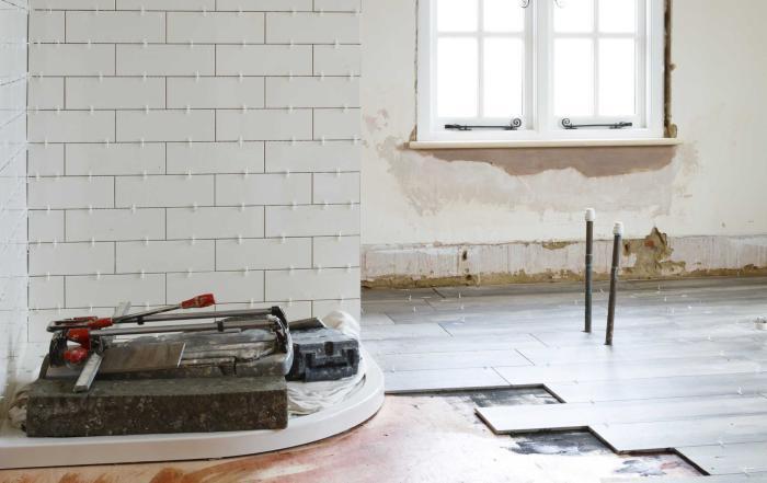 Fliesenleger bei der Arbeit: Wandfliesen und Bodenfliesen werden verlegt. Werkzeug und Fenster sichtbar. Renovierung 140-1024x614.jpg