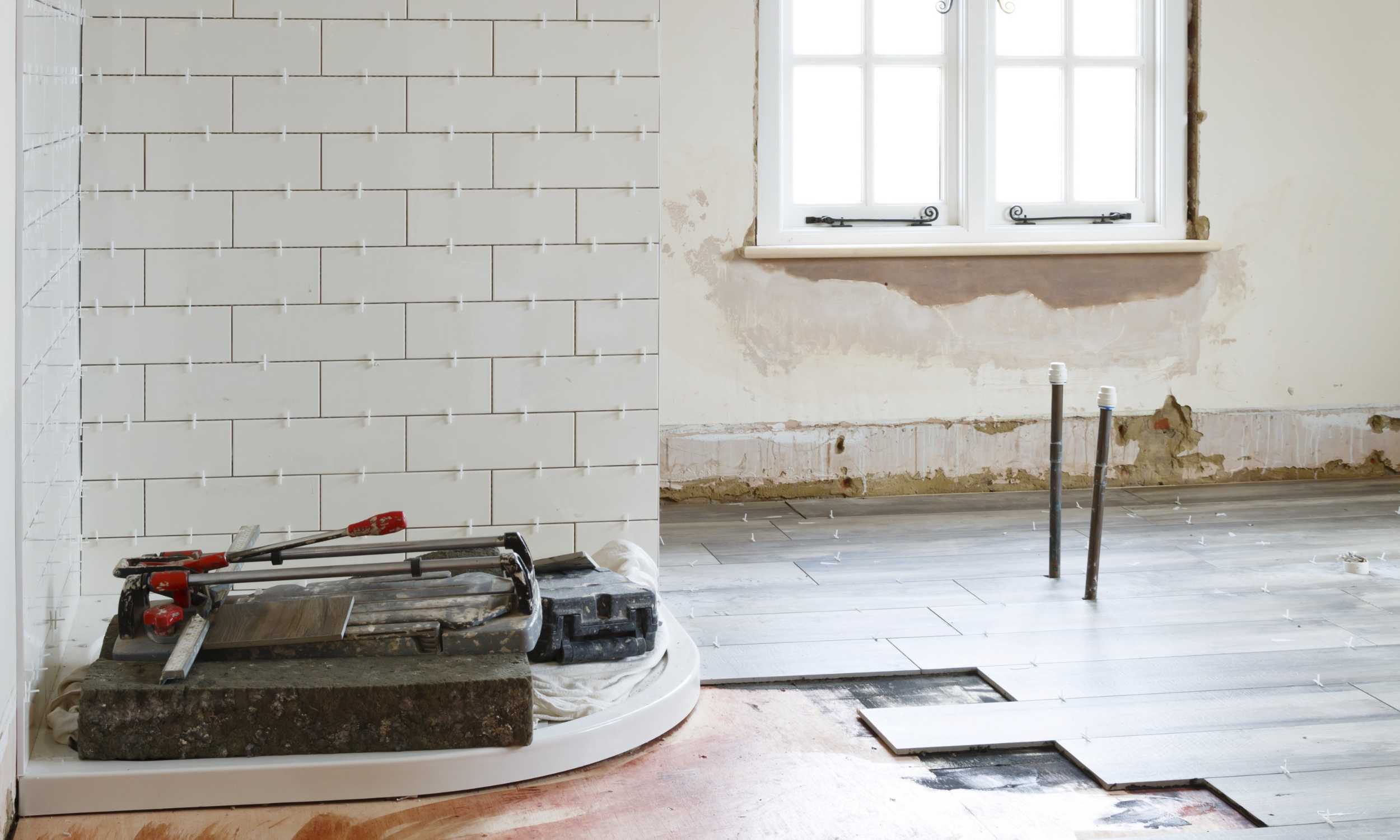 Fliesenleger bei der Arbeit: Wandfliesen und Bodenfliesen werden verlegt. Werkzeug und Fenster sichtbar. Renovierung 140-1024x614.jpg