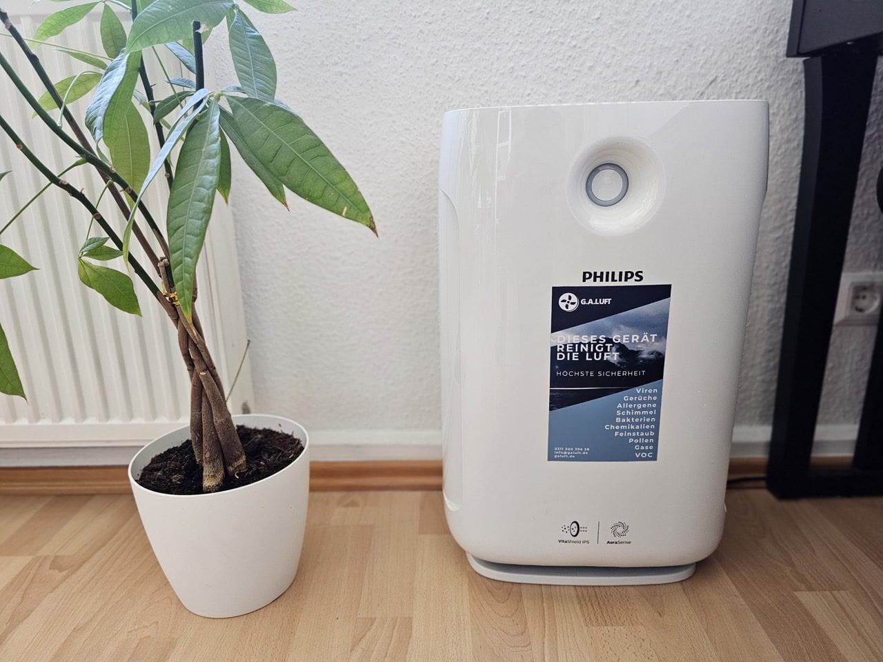 20230810_131956 Large_2000_Series_Luftreiniger_fuer_grosse_Raeume AC2887_10 Das Foto zeigt den Philips 2000 Series Luftreiniger AC2887/10, ein elegantes und modernes Gerät, das speziell für große Räume konzipiert ist. Das in einem stilvollen Weiß gehaltene Gehäuse verleiht dem Luftreiniger eine saubere und minimalistische Ästhetik, die sich nahtlos in jedes Interieur einfügt. Im Vordergrund des Luftreinigers befindet sich der Luftqualitätssensor, ein Schlüsselelement dieses Modells, der die Luftqualität in Echtzeit überwacht und anzeigt. Die Farbcodierung auf dem Display informiert den Benutzer schnell über die Luftqualität im Raum, wobei Blau für gute und Rot für schlechte Luftqualität steht. Das Gerät verfügt über mehrere Filterstufen, darunter ein HEPA-Filter, der bis zu 99,97% der Allergene und Partikel bis zu einer Größe von 0,3 Mikrometern entfernen kann. Der große Lufteinlass und -auslass sind strategisch platziert, um eine optimale Luftzirkulation zu gewährleisten. Mit seinen schlanken Abmessungen und dem ergonomischen Griff bietet der Philips Luftreiniger AC2887/10 eine Mischung aus Funktionalität und Stil und stellt eine effiziente Lösung dar, um eine gesündere und angenehmere Umgebung in Ihrem Wohnraum zu schaffen.