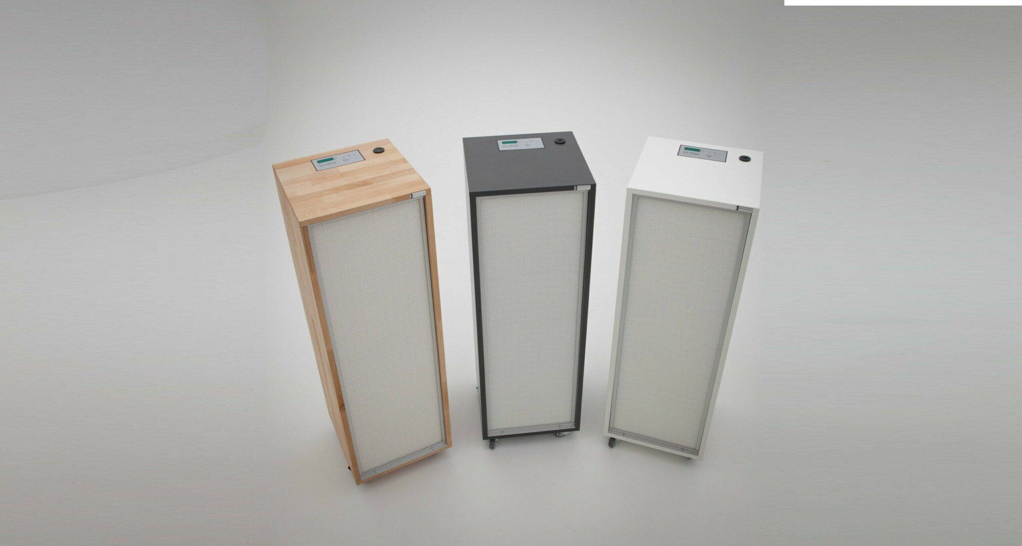 Drei Benchalist AIR CLEANER COMPACT Luftreiniger in Buche, Weiß und Anthrazit, entwickelt, um SARS-Viren, Bakterien und Staubpartikel zu filtern.