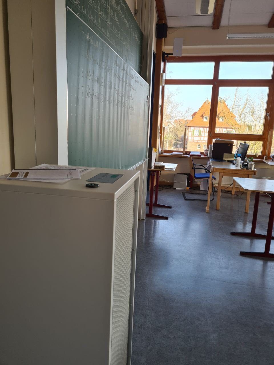 Kompakter Luftreiniger Benchalist in Klassenzimmer. Luftfilter für bessere Luftqualität, mit Tafel, Tischen und Fenster. Foto 2023.