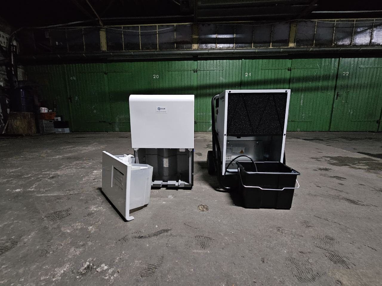 Luftentfeuchter Mietgeräte: Zwei Luftentfeuchter, einer mit offenem Wassertank, im Lagerraum. Photo_2023-11-28-14.54.36.