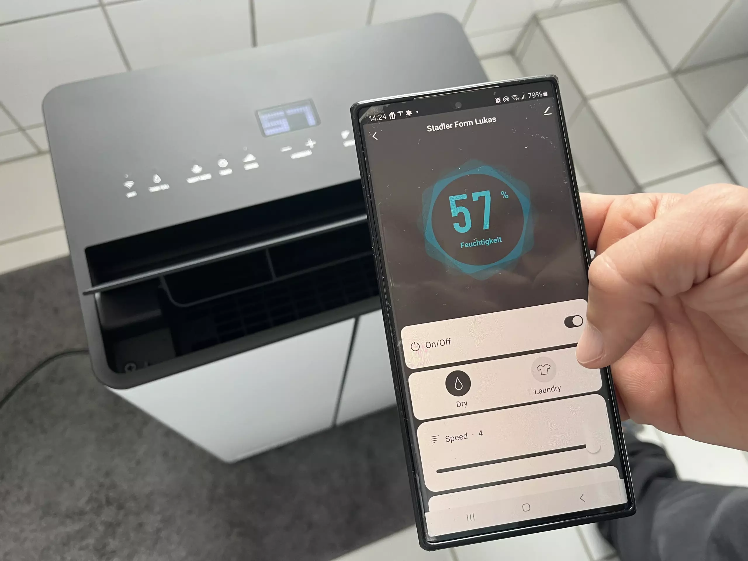 Smartphone App im Vordergrund. Luftentfeuchter Lukas von Stadler Form im Huntergrund