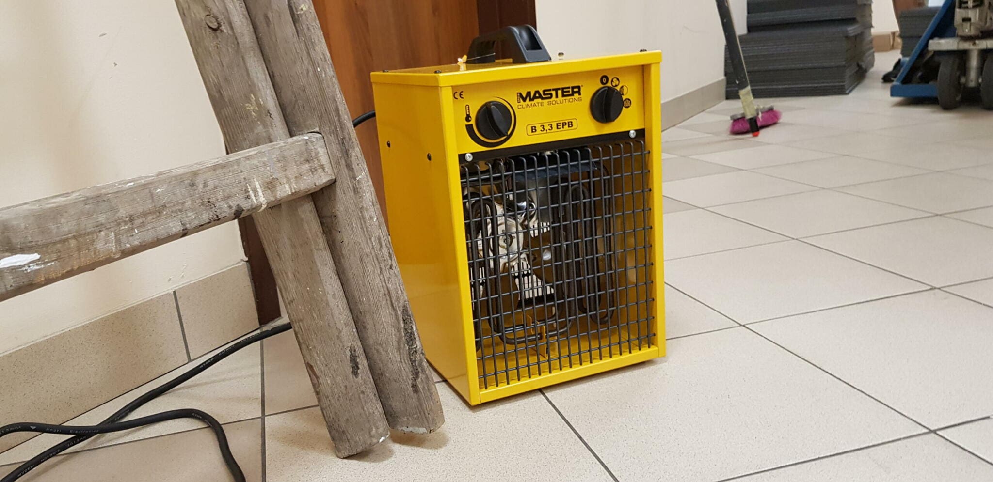 Gelber Master B 3.3 EPB Heizlüfter bei Renovierung. Leiter lehnt an Wand. Ideal für Baustellen. Klimatisierungslösung.