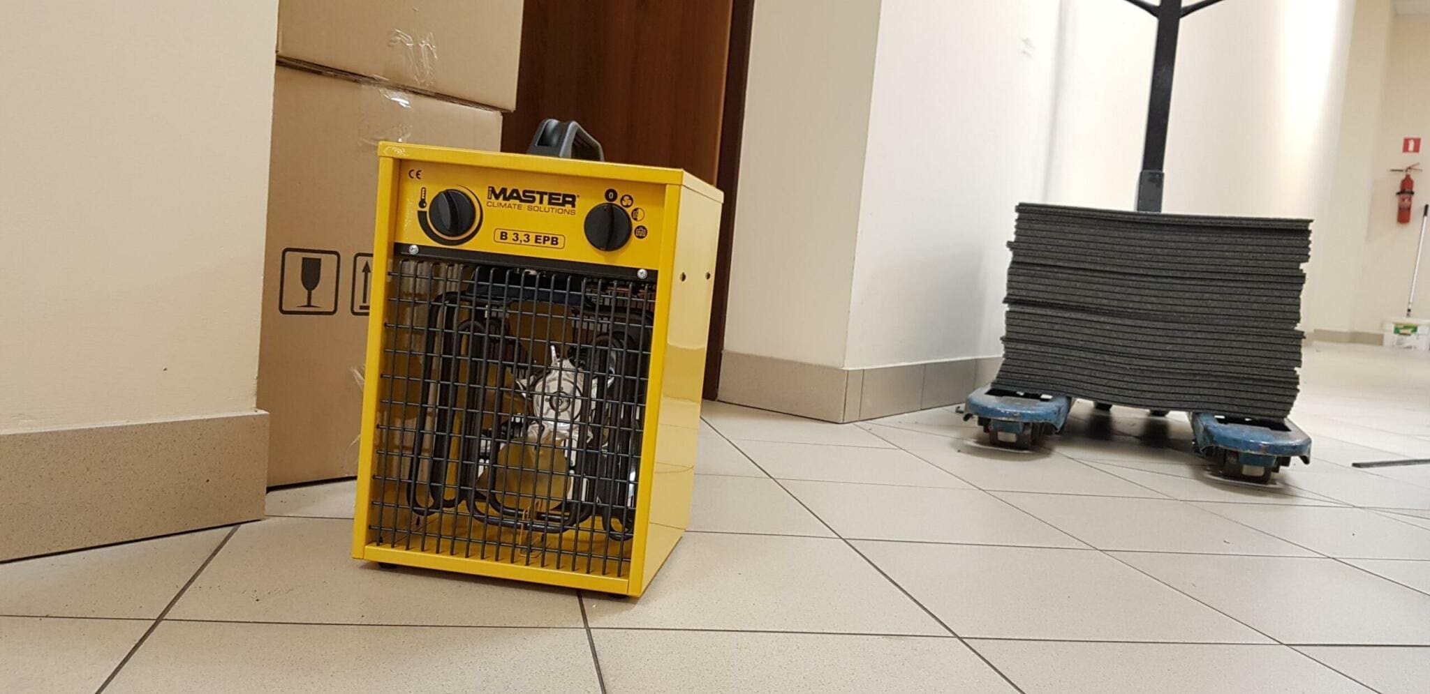 Gelber Master B 3.3 EPB Heizlüfter bei Renovierung. Kartons, Fliesen und Baumaterialien im Hintergrund. Heizung für Baustelle.