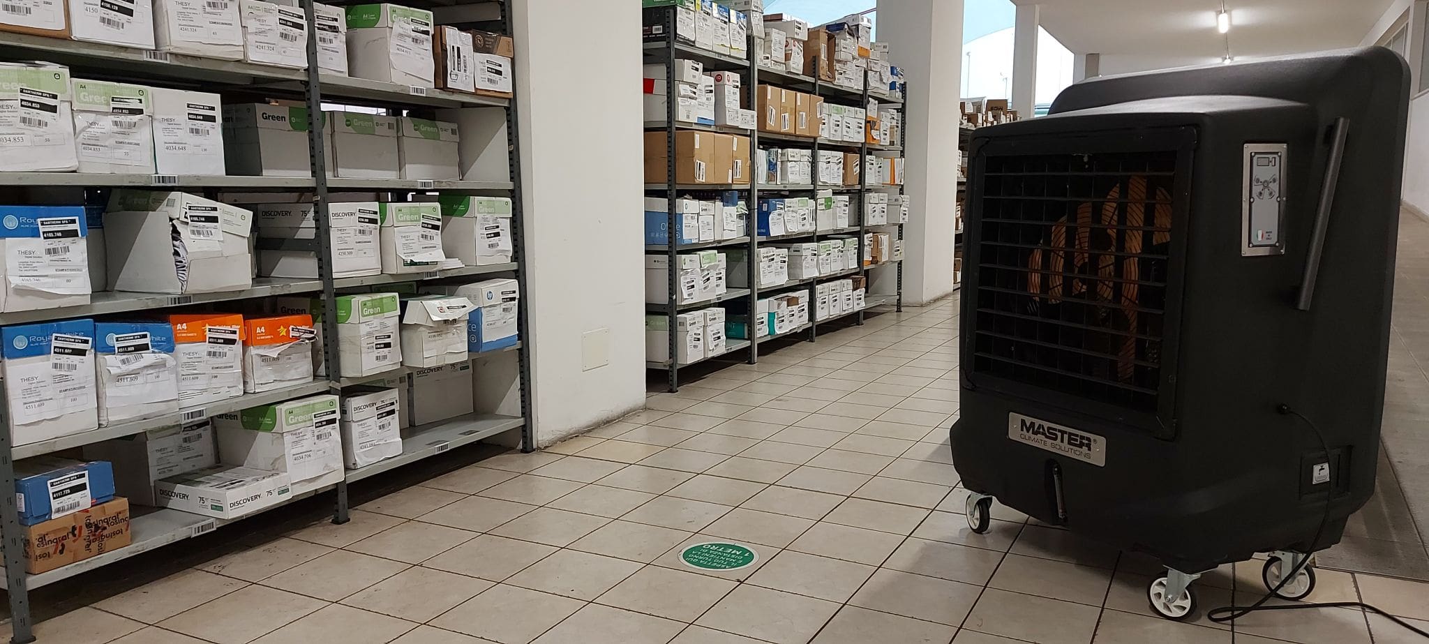Lagerraum mit Regalen voller Kartons und einem mobilen Master BC-221 Shop Kühler. Optimale Lagerung im Einzelhandel.