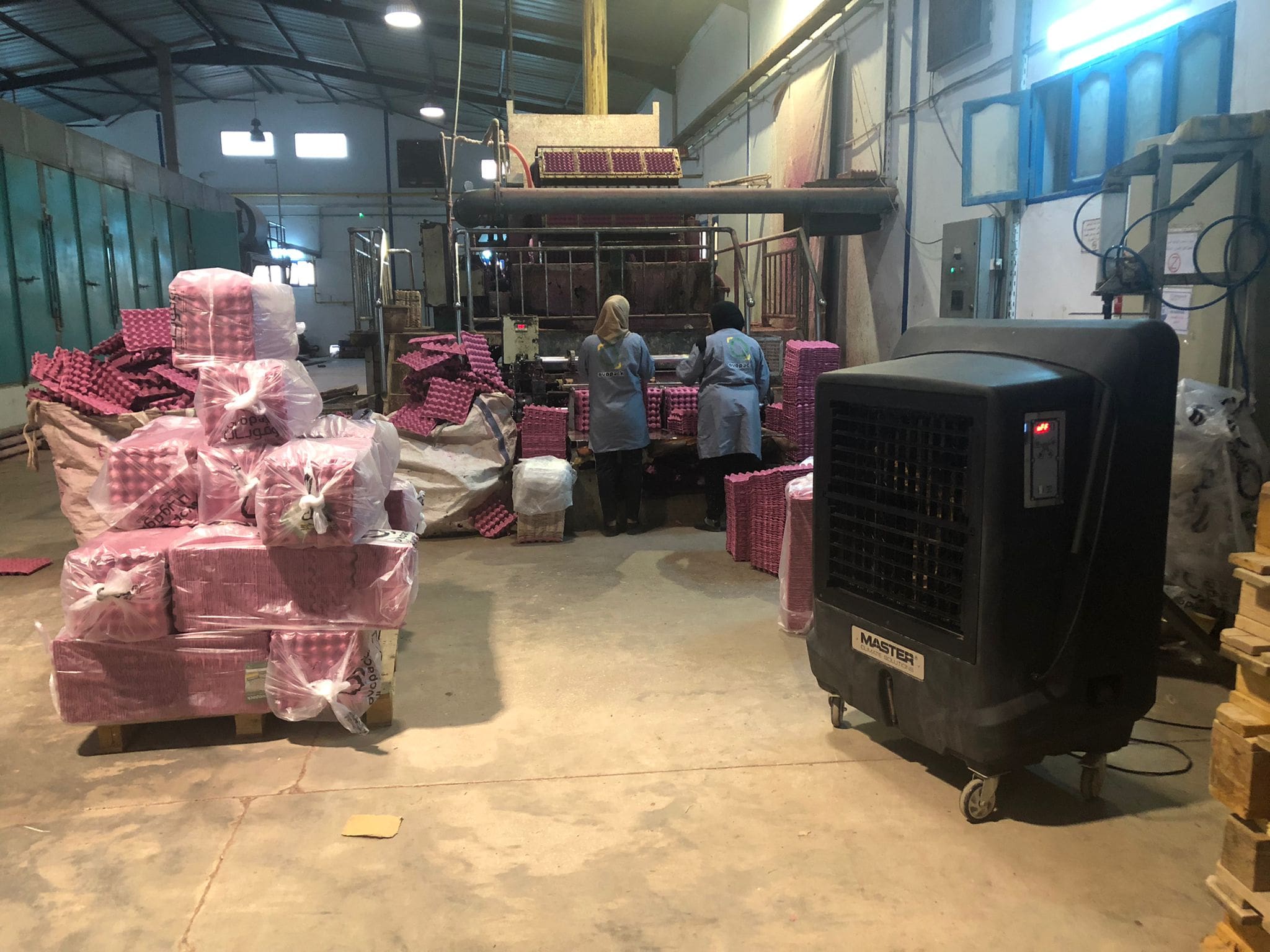 Textilproduktion Afrika: Arbeiterinnen an Maschine, Paletten mit Textilprodukten. Master-BC-221 im Vordergrund.