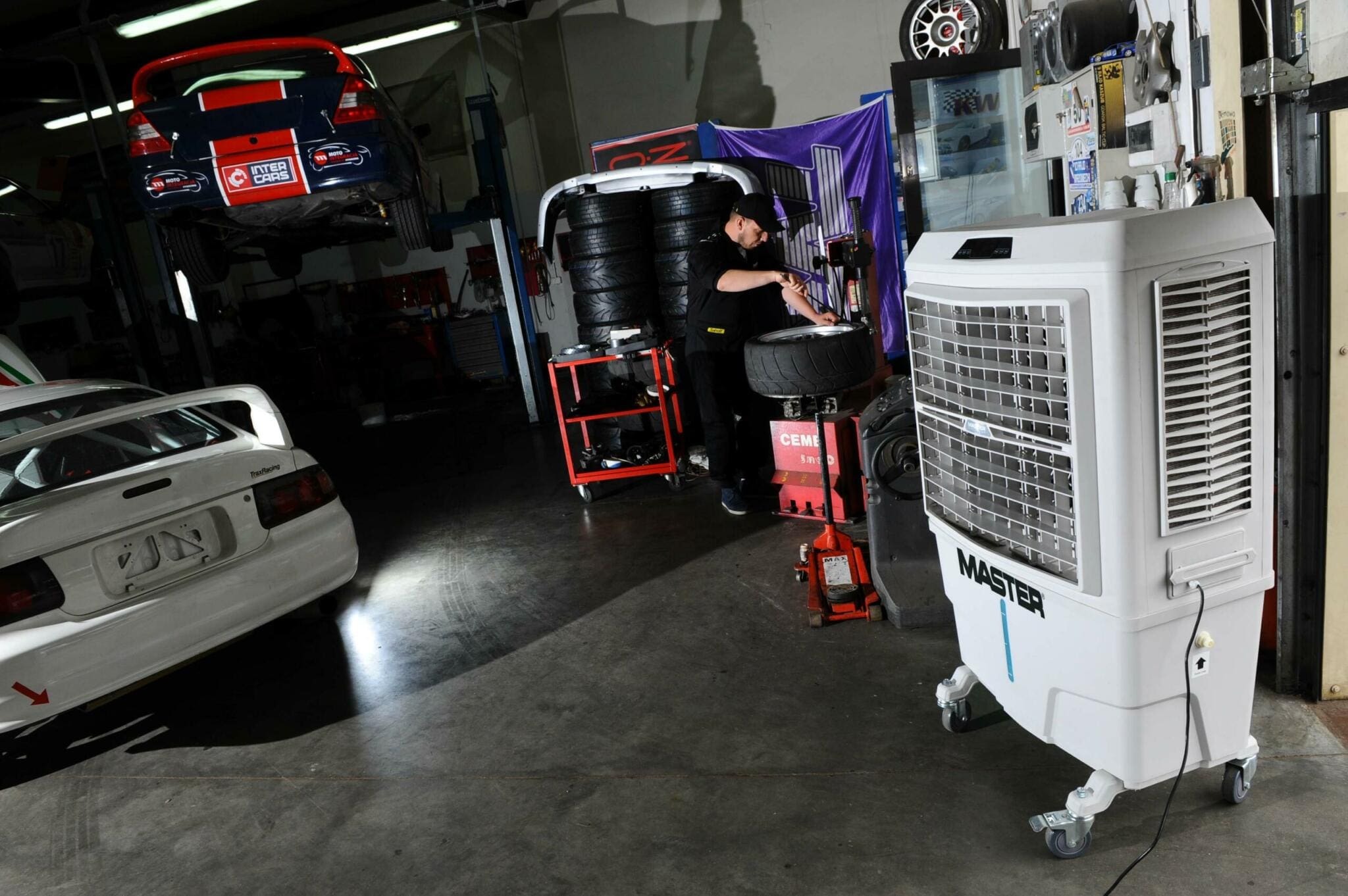 Werkstatt mit Master BC 80 Kühler, Autos im Service. Reifenwechsel, Hebebühne, Werkzeugwagen. Fachpersonal im Einsatz.