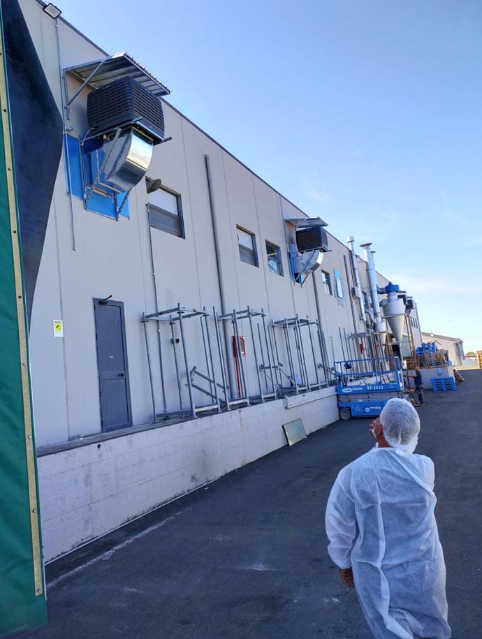 BCM-Installation an Außenwand der Lebensmittelindustrie. Lüftungsanlage, Arbeiter in Schutzkleidung, blaue Hebebühne.