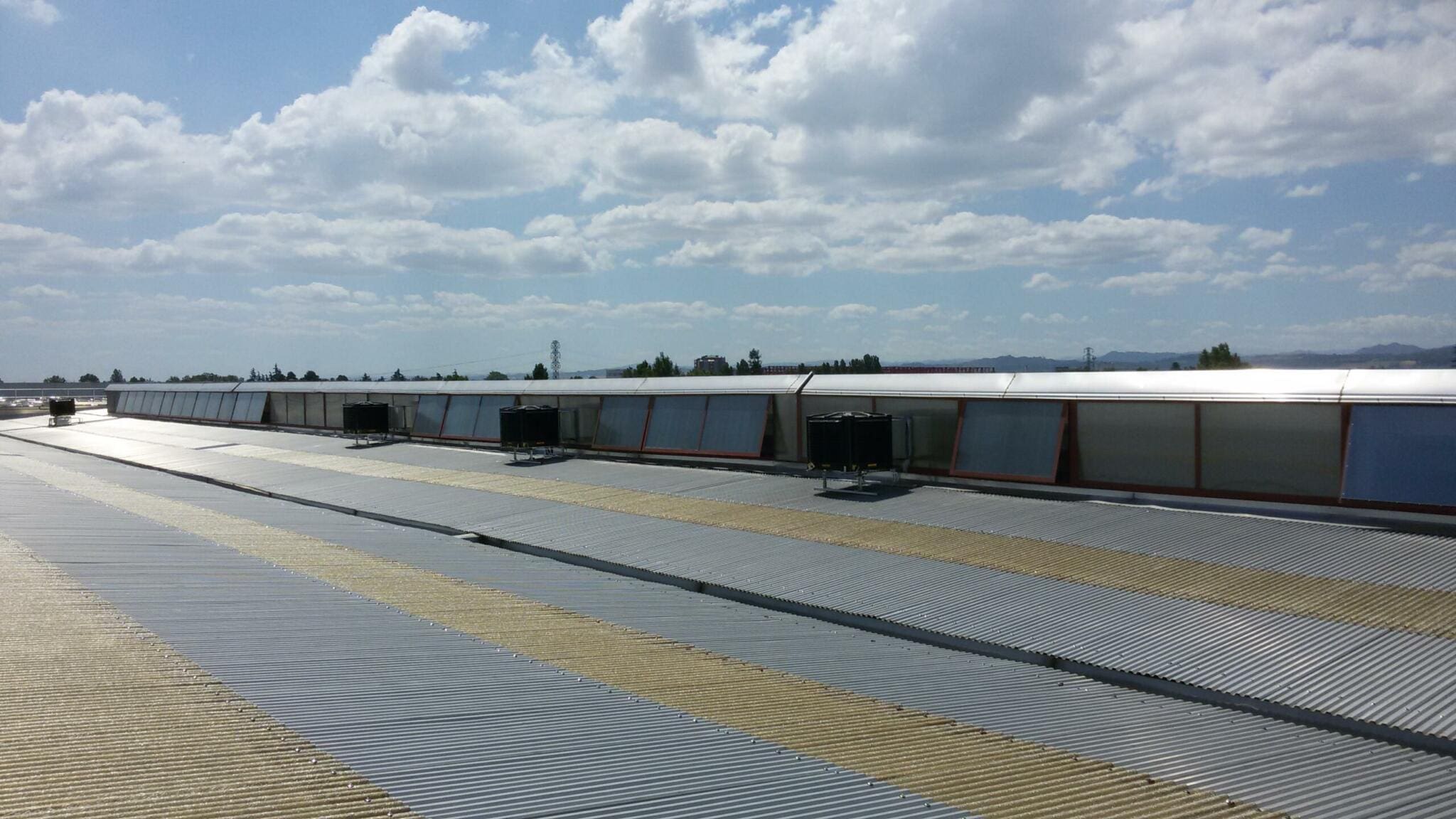 BCM Dachinstallation: Wellblechdach mit Oberlichtern und Tanks. Master-BCM-Dachinstallation unter blauem Himmel.
