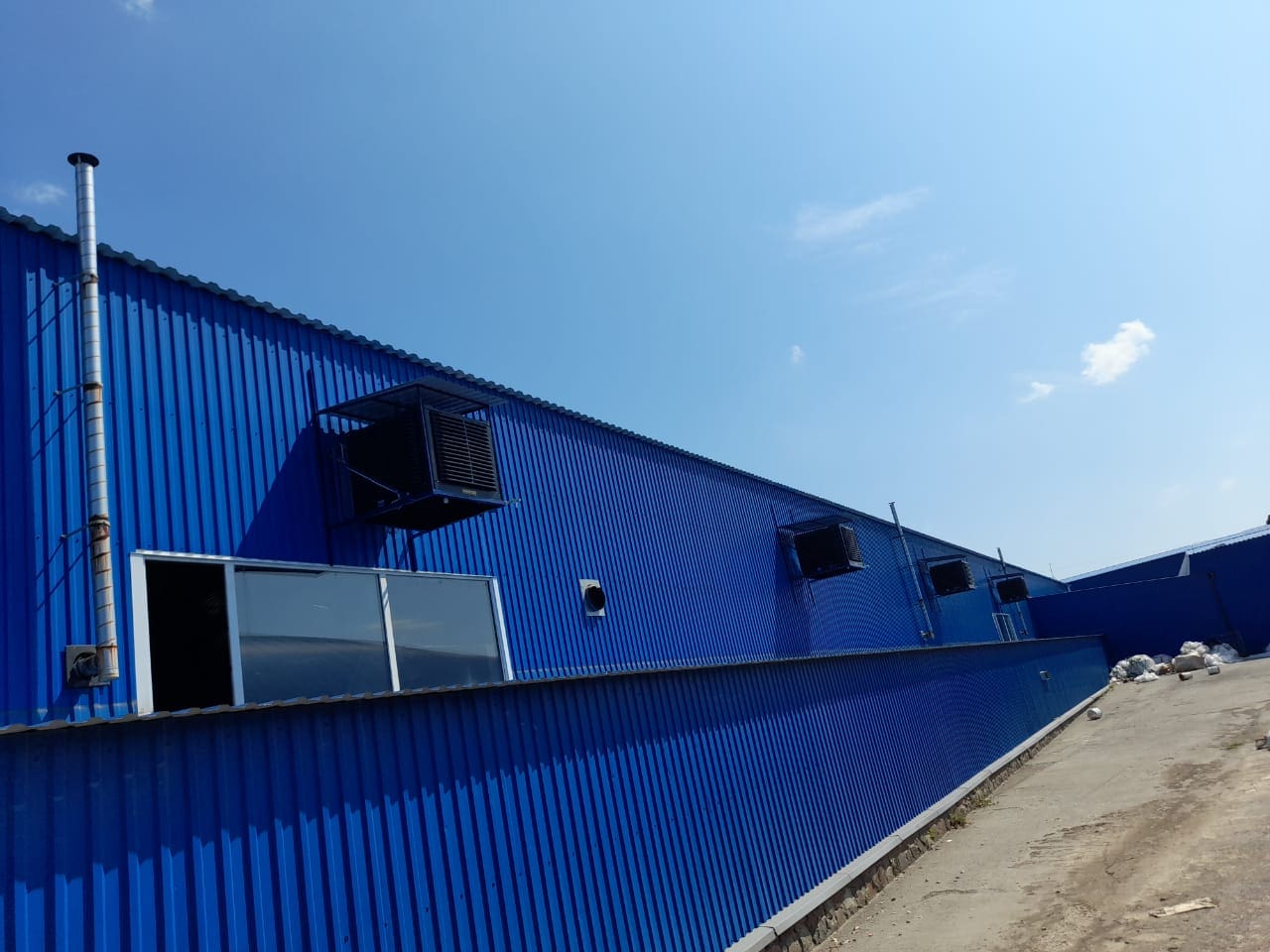 Blaue BCM-Wandinstallation mit offenem Fenster. Metallfassade mit Lüftung und Rohr. Architektur und Gebäudeinstallation im Aussenbereich.