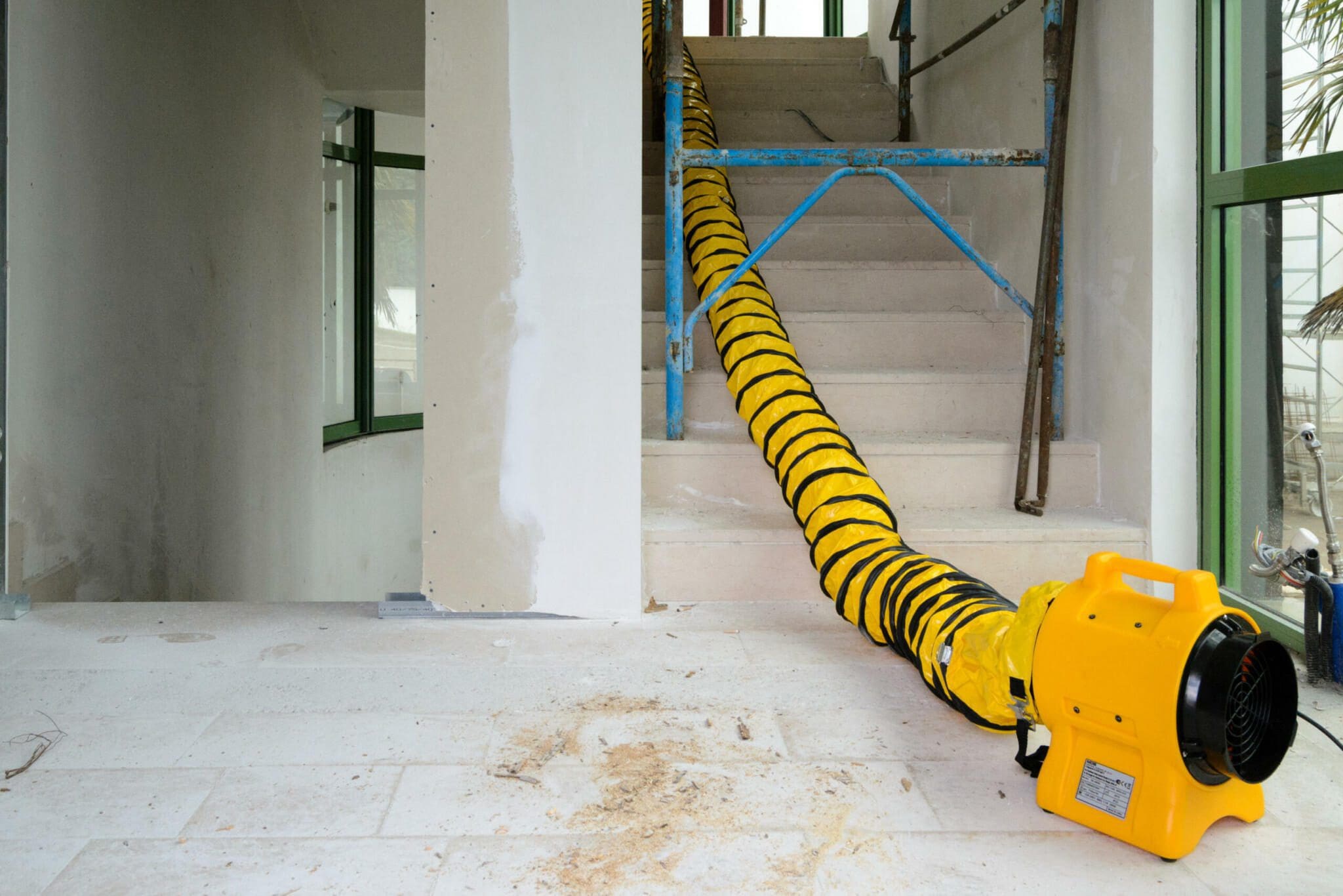 Master BL-4800 Bautrockner mit Schlauch auf Baustelle. Gelber Ventilator zur Trocknung, Treppe im Hintergrund. Bauarbeiten mit Belüftung.