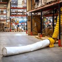 Master BL-4800 Entstauber mit Staubbeutel im Lager. Gelber Entstauber mit weißem Staubbeutel auf dem Boden eines Lagers.