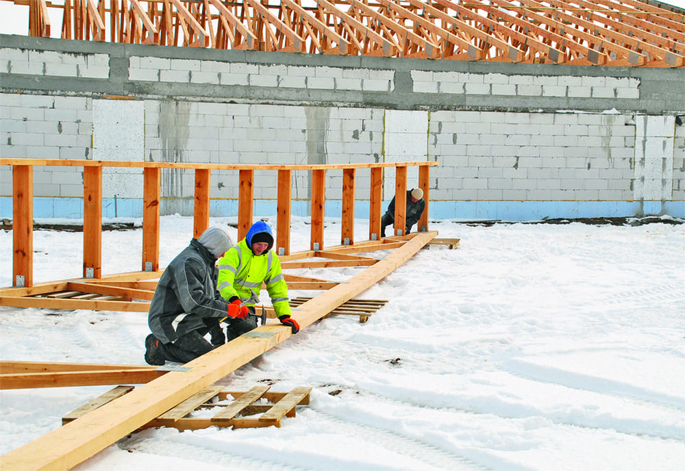 Bauarbeiter im Freien bei Montage von Holzkonstruktion. Rohbau mit Holzbalken und Schnee. Master-BLP-17MDC.