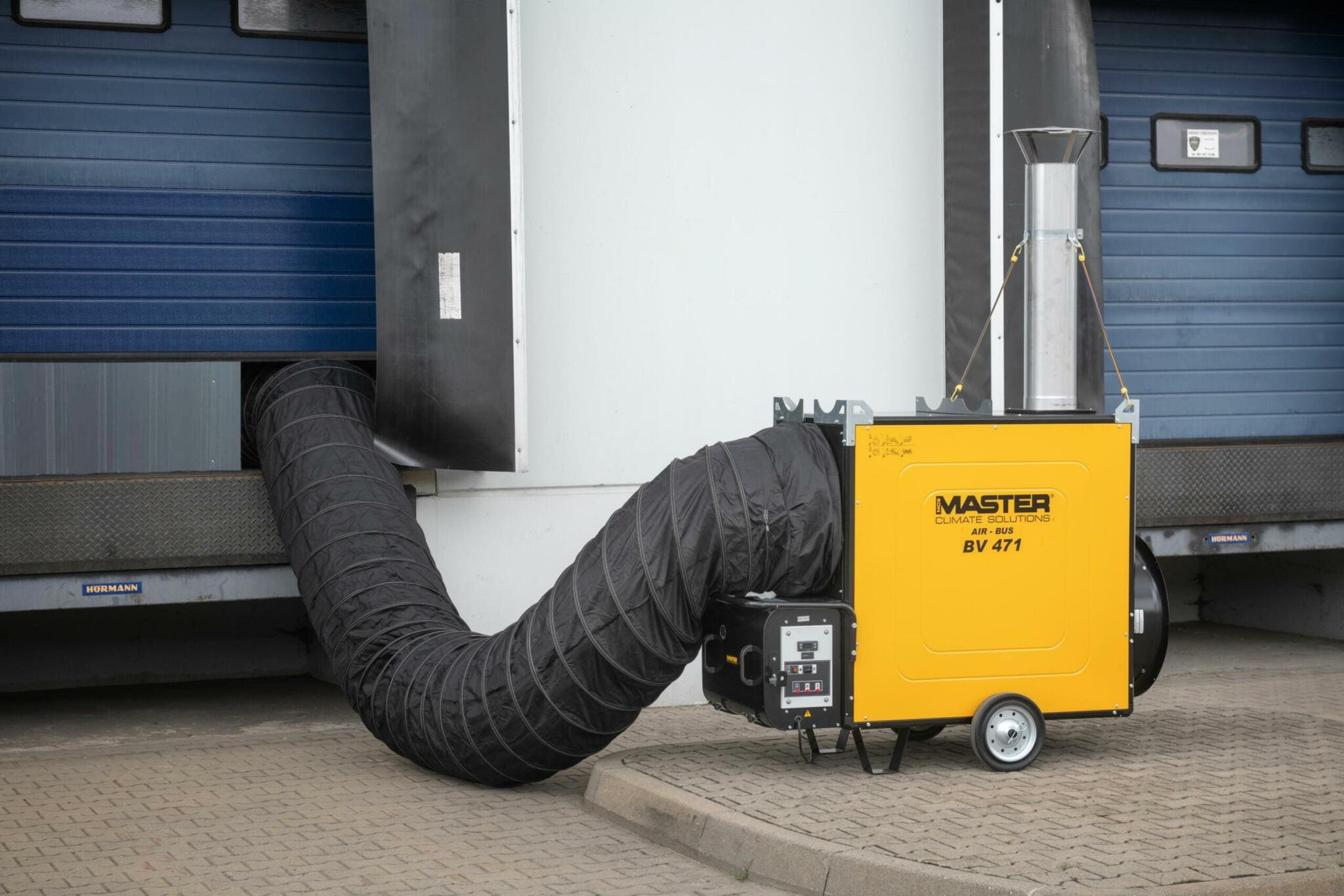 Master BV 471 Ölheizer außen mit Schlauch vor Industrietor. Mobile Heizung für Baustellen und Lagerhallen.