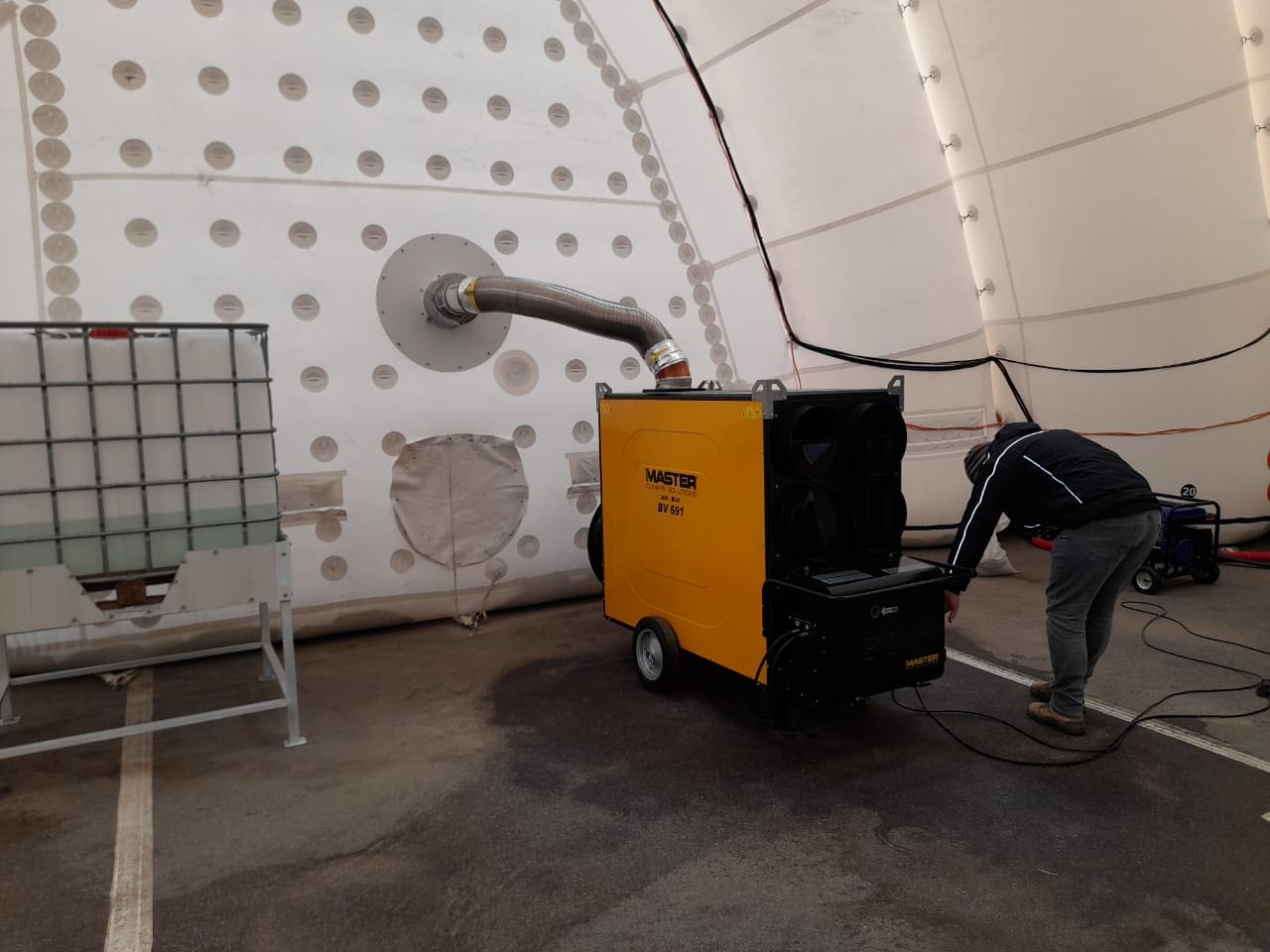 Master BV 691 Heizung im Flugzeughangar. Pneumatische Halle mit Heizgerät. Mann bedient die Heizung. Warmluftheizung für Hallen.
