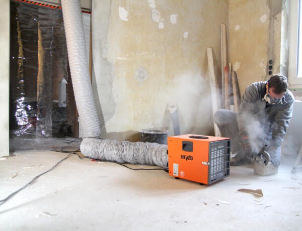 Heylo PF1400 DCS System im Einsatz: Arbeiter mit Staubmaske, Entstaubungssystem, Renovierung, Baustelle. Staubabsaugung.