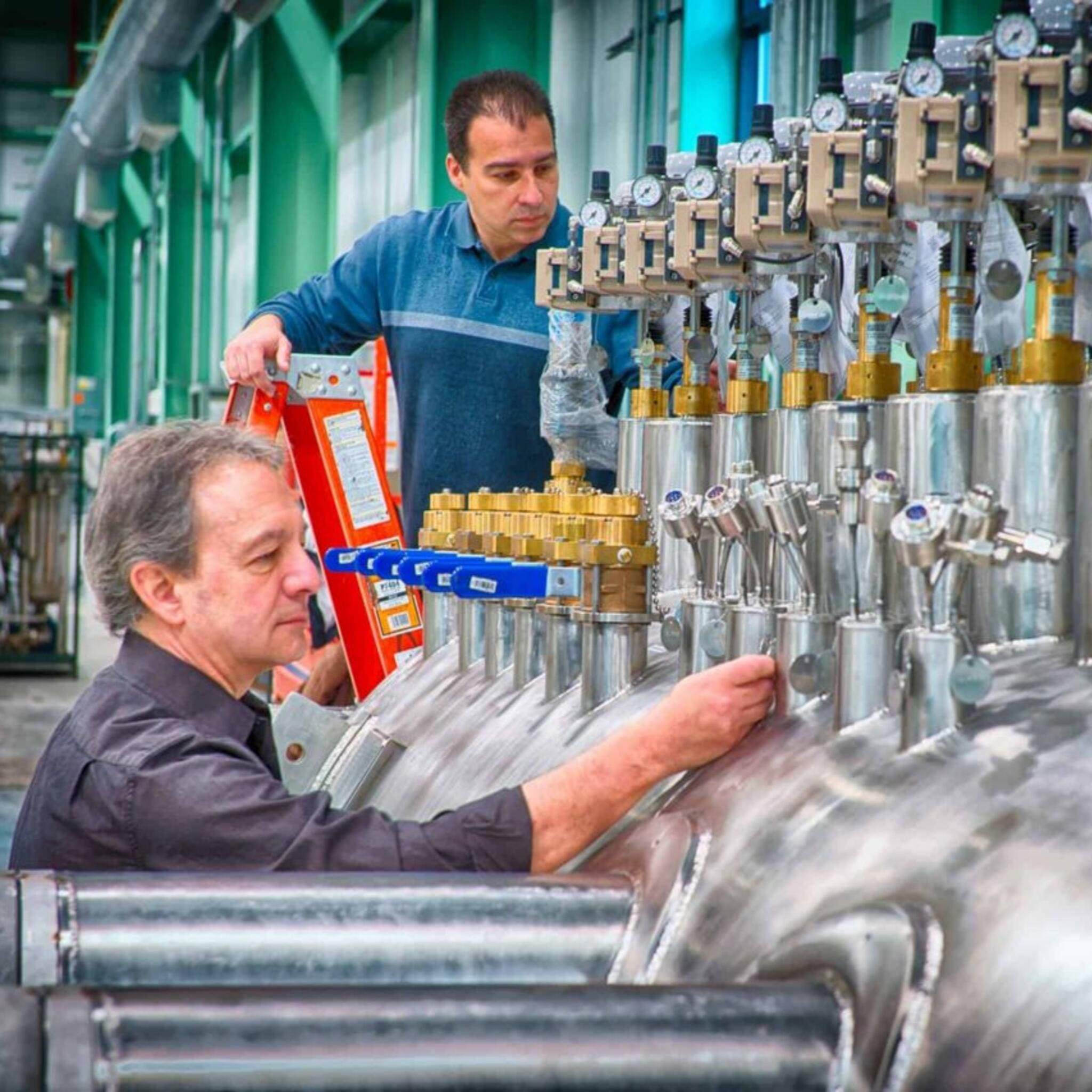 Industrie Luftbefeuchter. Zwei Techniker prüfen/warten eine große Industrieanlage. Luftbefeuchter mieten für Industrieanwendungen.