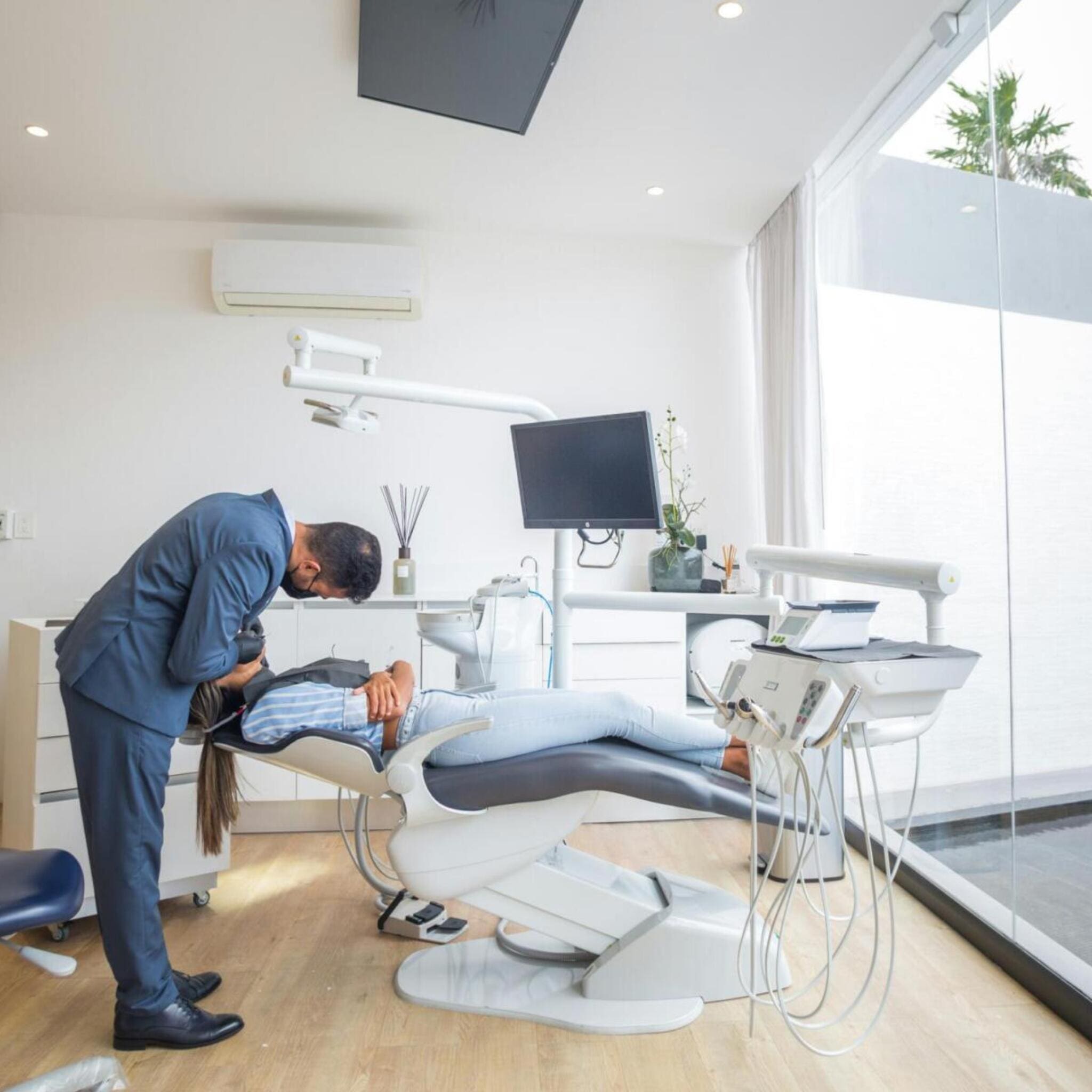 Luftbefeuchter Praxis: Zahnarzt untersucht Patientin im Behandlungsstuhl. Helle Praxis mit moderner Ausstattung.