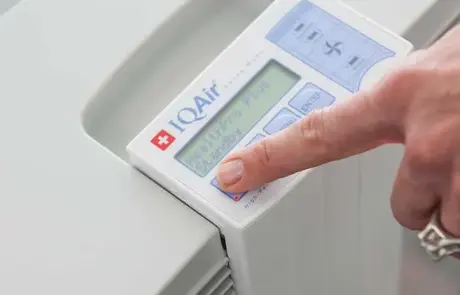 IQAir HealthPro 250 NE Luftreiniger Bedienung Nahaufnahme des IQAir HealthPro 250 NE Luftreinigers: Bedienfeld mit Finger, weiße Ausführung. Ideal für Allergiker & Asthmatiker.