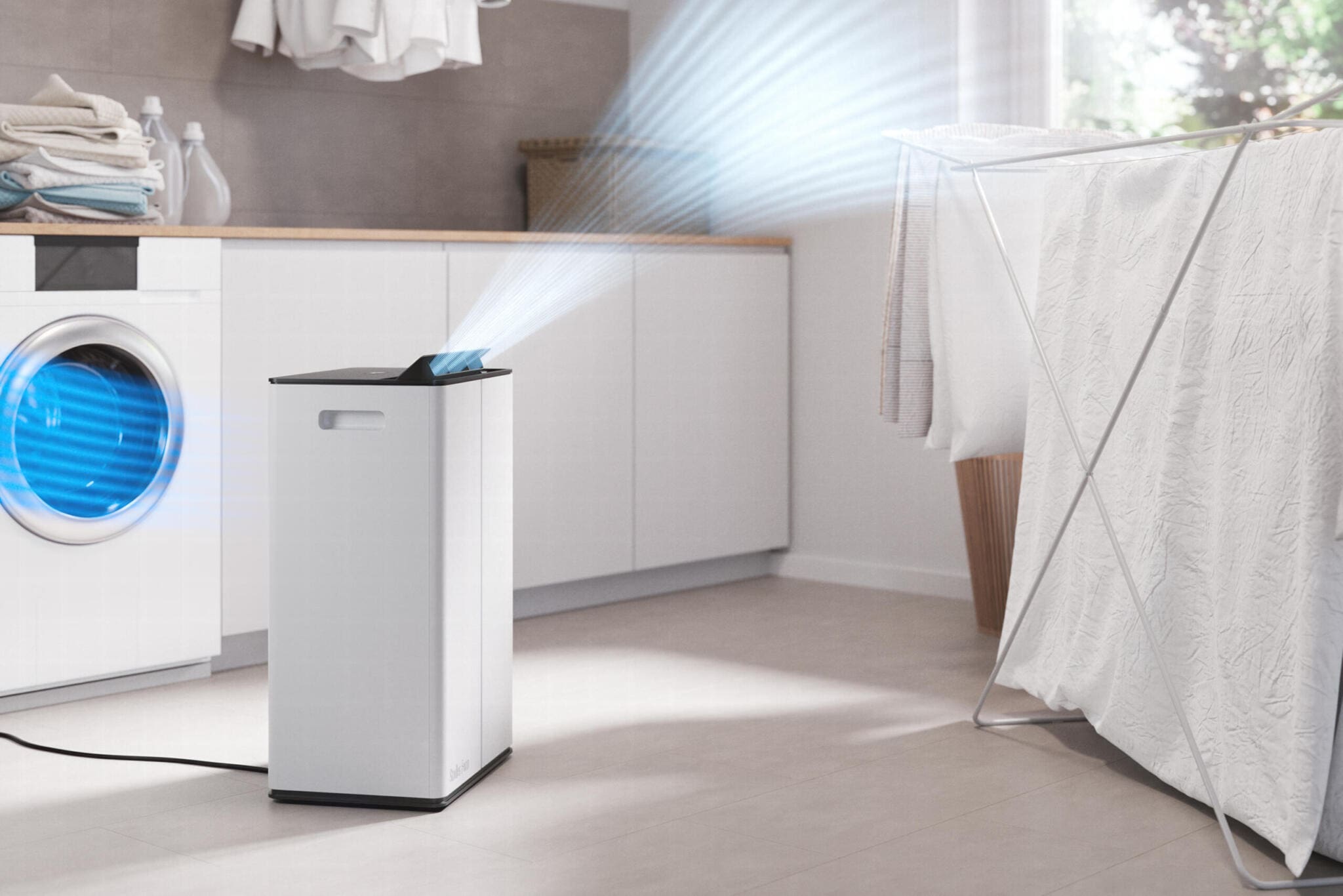 Stadler Form Lukas Pro Luftentfeuchter mit HEPA-Filter im Einsatz neben Wäscheständer und Waschmaschine. Luftreiniger im modernen Bad.