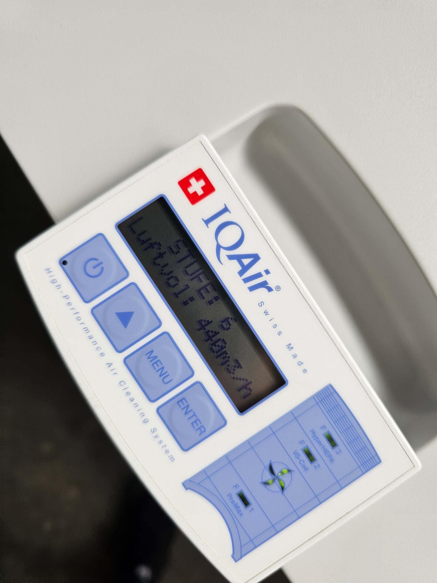 Nahaufnahme des Bedienfelds des IQAir HealthPro 250 NE Luftreinigers. Fokus auf Display, Tasten und Filteranzeigen. Weißes Gehäuse, blaue Akzente.