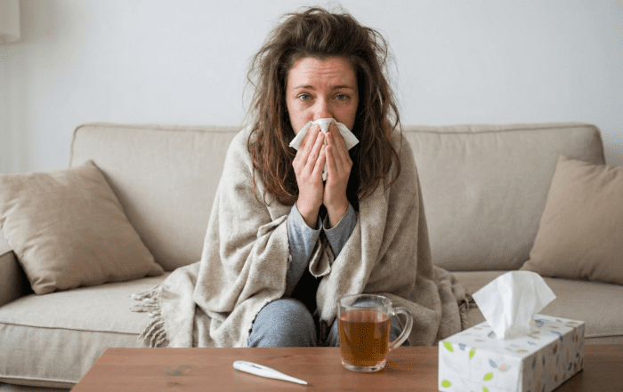 Frau mit Erkältungssymptomen, die sich in eine Decke gehüllt hat. Luftreiniger gegen Viren helfen bei Grippe, Corona & Erkältung. GALuft.