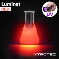 Luminat Red: Laborglas mit roter Flüssigkeit leuchtet unter UV-Licht. Ideal für Experimente und Forschung im Labor.