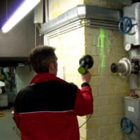 Ein Mann untersucht mit einer Luminat-Gelb-Lampe eine Wand auf Lecks. Die Fluoreszenz macht Undichtigkeiten sichtbar. 3510012014_Luminat-Yellow