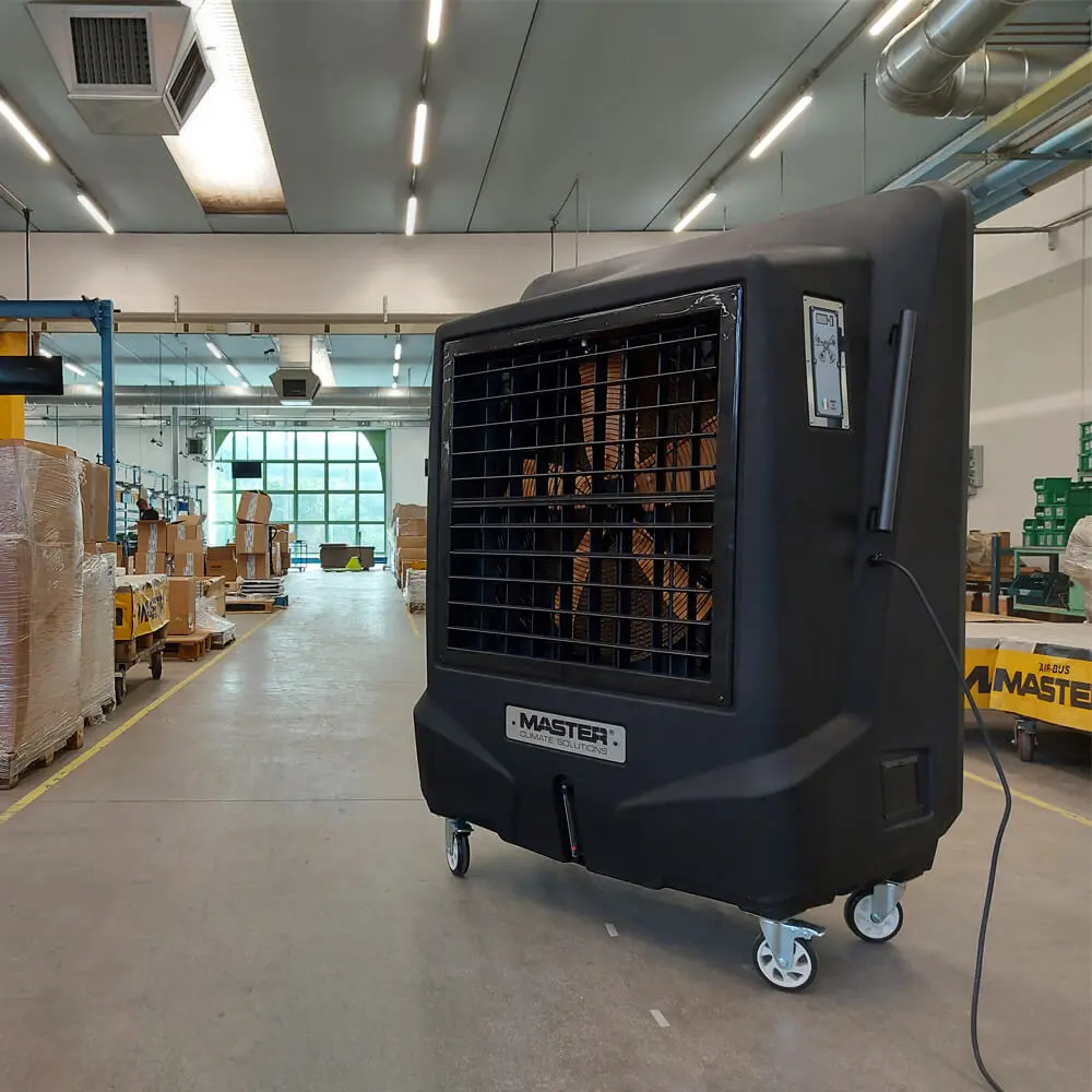 Mobiler Luftkühler BC 220 in einer Lagerhalle, schwarzes Gerät mit großen Lüfterflügeln auf Rollen für industrielle Kühlung.
